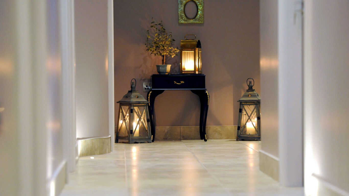 Elegant corridor with ambient lantern lighting on tiled floor, featuring stylish decor and warm, welcoming atmosphere.