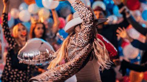 Guests dancing at a vibrant hotel party with colourful balloons and festive lights, enjoying a lively and joyous atmosphere.