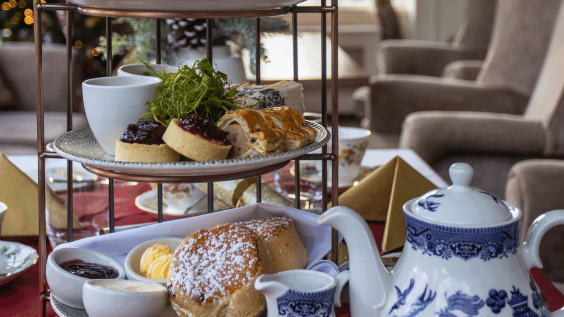 Elegant afternoon tea setup with scones, pastries, and fine china in a cosy hotel lounge for a relaxing experience.