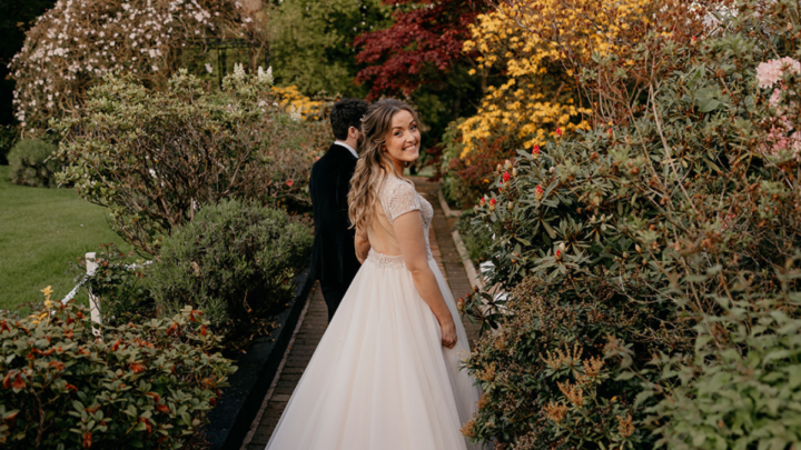 Bride smiles in lush garden with colourful flowers, perfect for a picturesque wedding venue at our charming hotel.
