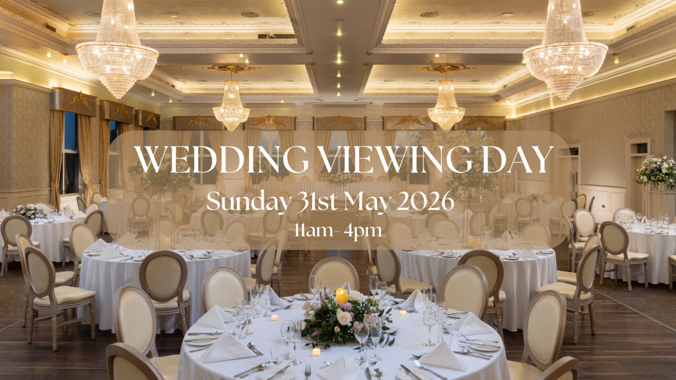 Elegant ballroom with chandeliers set for a wedding; round tables with floral centrepieces, inviting ambiance.