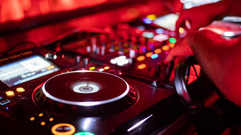 Vibrant hotel bar with live DJ mixing music on illuminated deck, creating an energetic nightlife experience for guests.