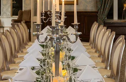 Elegant dining room with candlelit table, plush seating, chandeliers, and classic decor for a luxurious hotel experience.