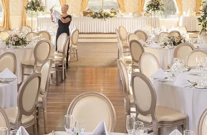 Elegant ballroom with chandeliers, floral centrepieces, and table settings for a luxurious hotel event experience.