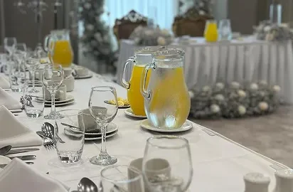 Elegant banquet setup with crisp white linens, fresh juice pitchers, and a floral arch, perfect for weddings or events.
