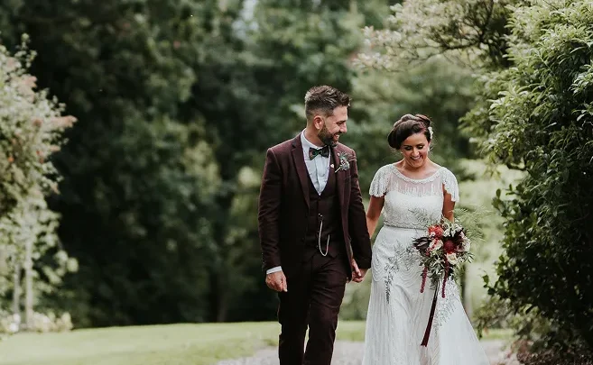 Romantic couple walking in lush hotel garden, ideal for weddings, surrounded by greenery and scenic beauty.