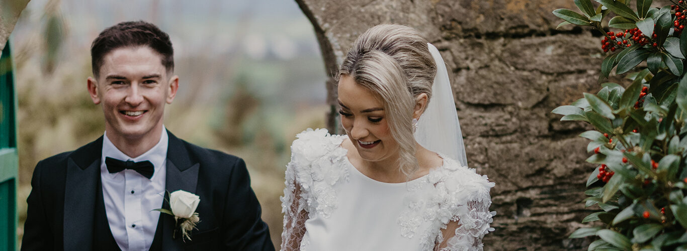 Charming wedding couple by stone archway and vibrant greenery at countryside hotel, ideal for romantic escapes.